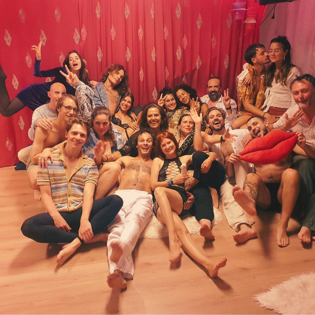 Temple participants smiling together in a group photo in front of a red curtain